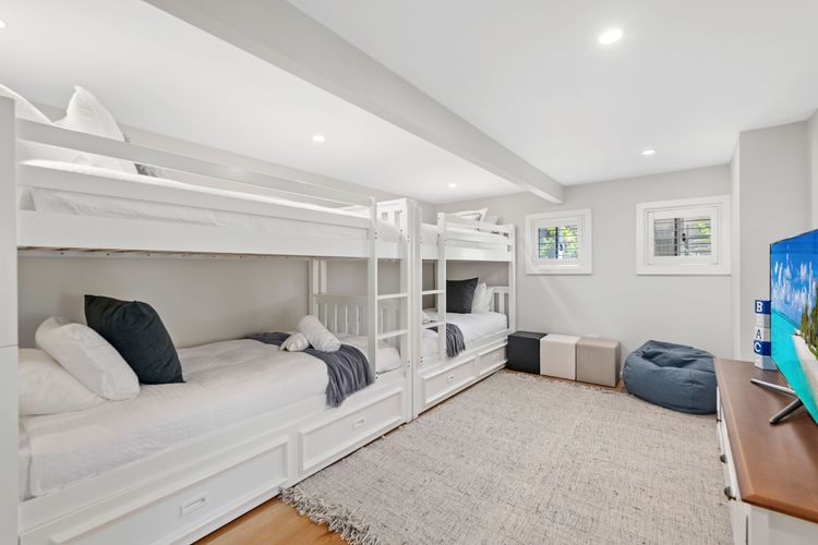 Bedroom 4 has 4 Single bunk beds, a TV, a built-in robe, a ceiling fan and air-conditioning.