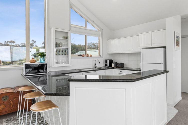 Fully equipped kitchen looks pristine, with its white cabinets contrasting with the black countertops and an island benchtop