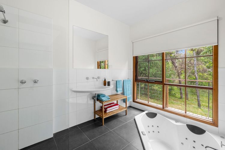 The main bathroom has a tidy and clean shower, spa bath, and toilet.