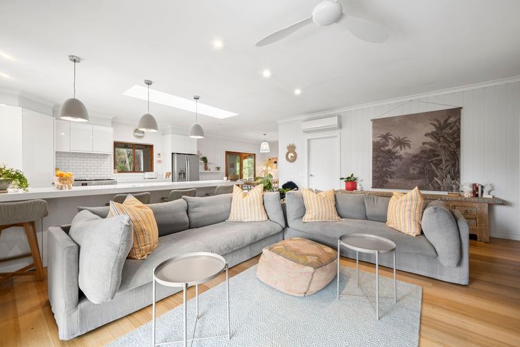 With its soothing neutral tones of elegant white walls, cosy grey couches, and accents of soft orange pillows, the living room is as welcoming and calming as it can be.