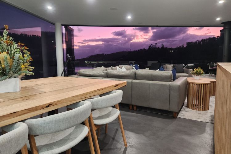 Full-height retractable glass doors open to a large entertaining balcony with glass balustrade