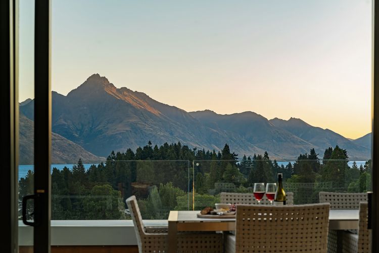 Expansive outdoor balcony with dining table, outdoor heaters, hanging chair, and incredible lake and mountain views.