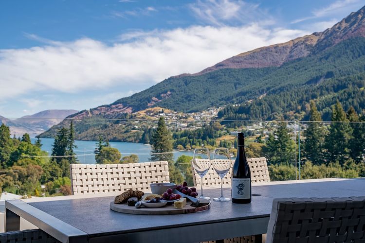 Expansive outdoor balcony with dining table, outdoor heaters, hanging chair, and incredible lake and mountain views.