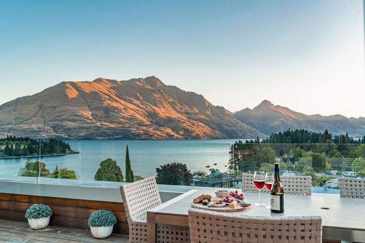 Expansive outdoor balcony with dining table, outdoor heaters, hanging chair, and incredible lake and mountain views.