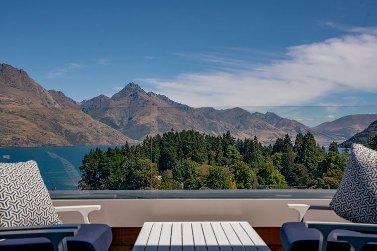 Expansive outdoor balcony with dining table, outdoor heaters, hanging chair, and incredible lake and mountain views.