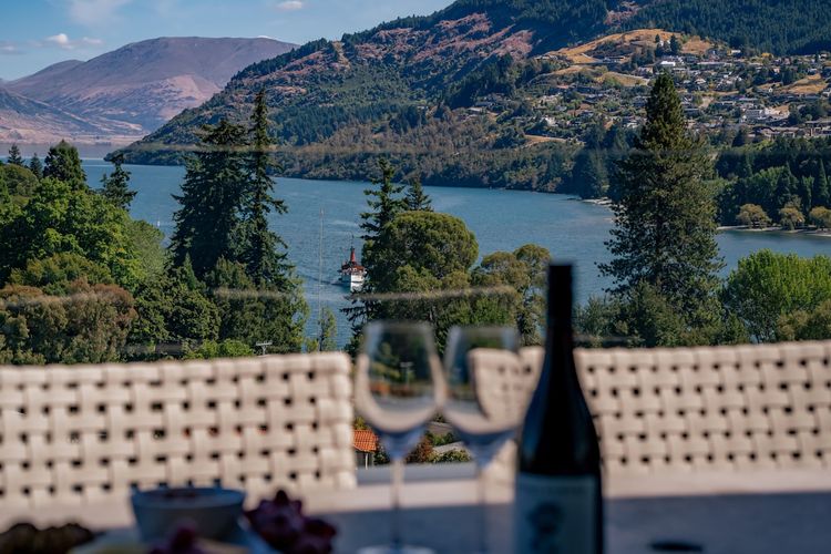 Expansive outdoor balcony with dining table, outdoor heaters, hanging chair, and incredible lake and mountain views.