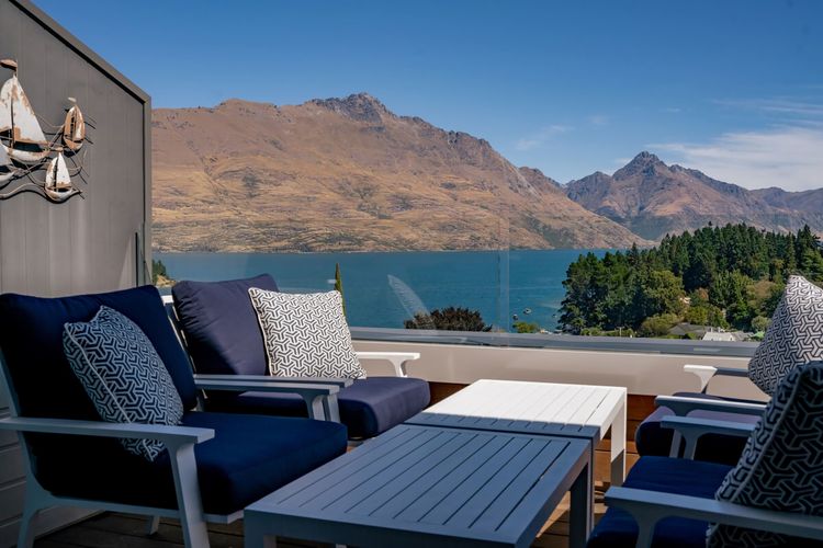 Expansive outdoor balcony with dining table, outdoor heaters, hanging chair, and incredible lake and mountain views.
