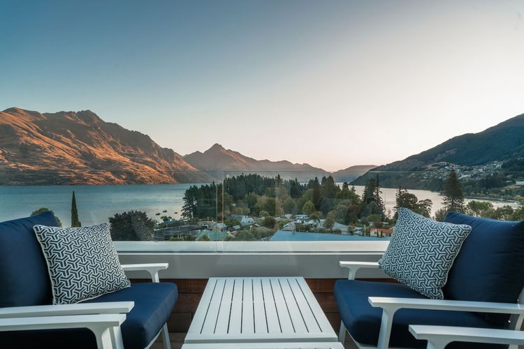 Expansive outdoor balcony with dining table, outdoor heaters, hanging chair, and incredible lake and mountain views.