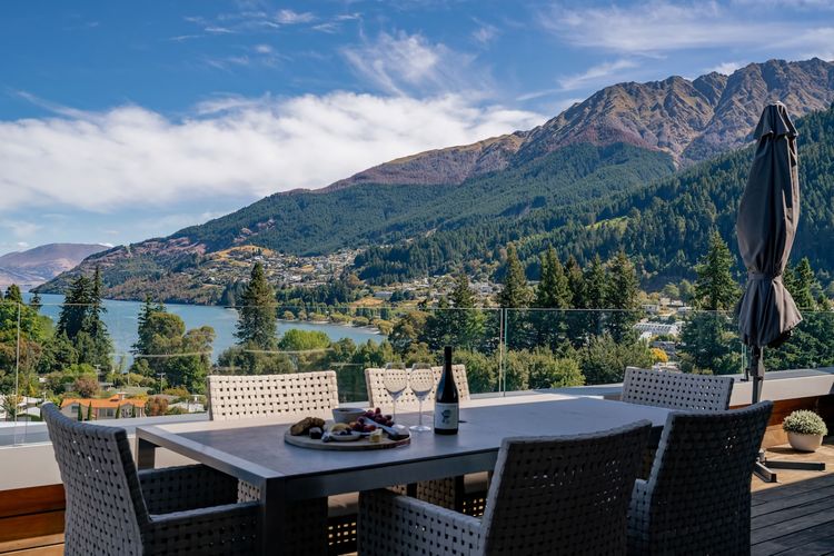 Expansive outdoor balcony with dining table, outdoor heaters, hanging chair, and incredible lake and mountain views.