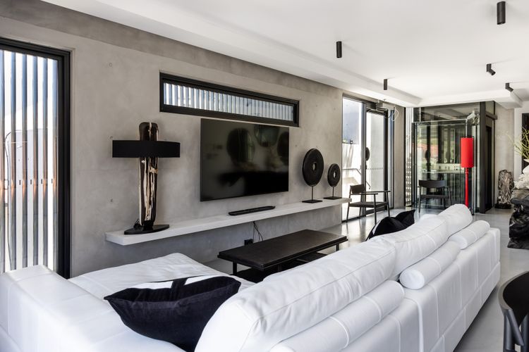 Lounge with concrete feature wall, large screen TV and sculptural art pieces.