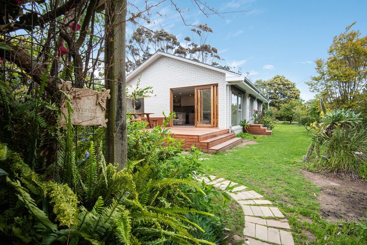 Lush greenery and trees surrounds the house.