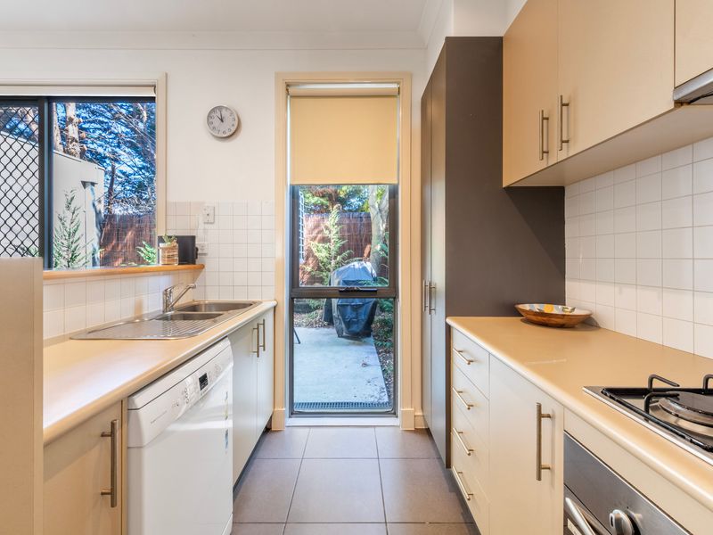 Kitchen sink and counter perspective positioned next to a bright window view.