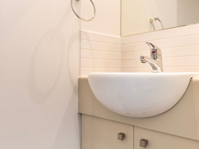 Close-up of the modern bathroom sink featuring a sleek chrome faucet and minimalist white vanity.