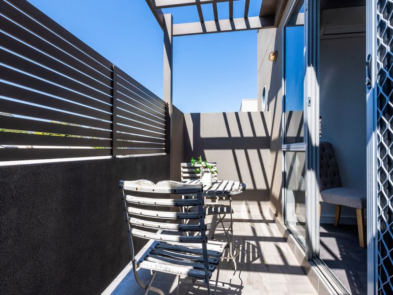 Private outdoor balcony terrace enclosed by modern black slatted privacy screening and patio seating.