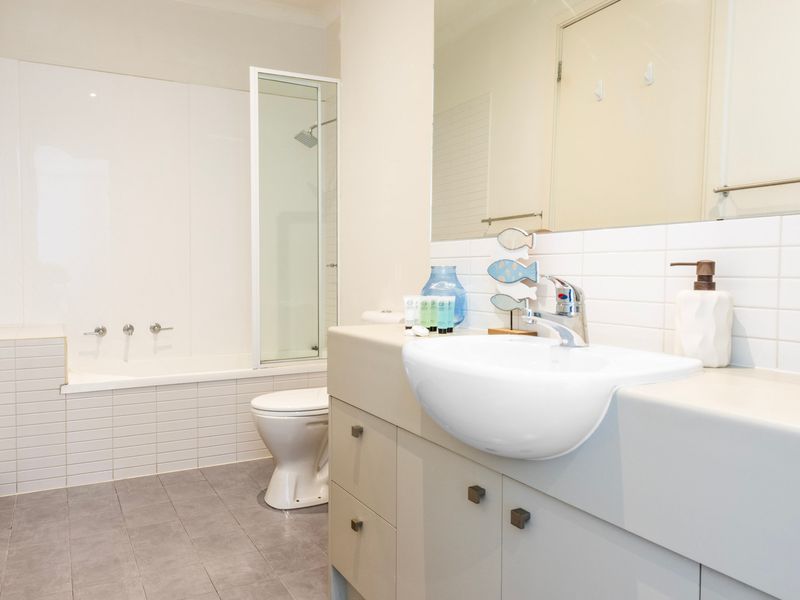 Modern bathroom equipped with a white vanity basin, glass-enclosed shower, and a toilet.