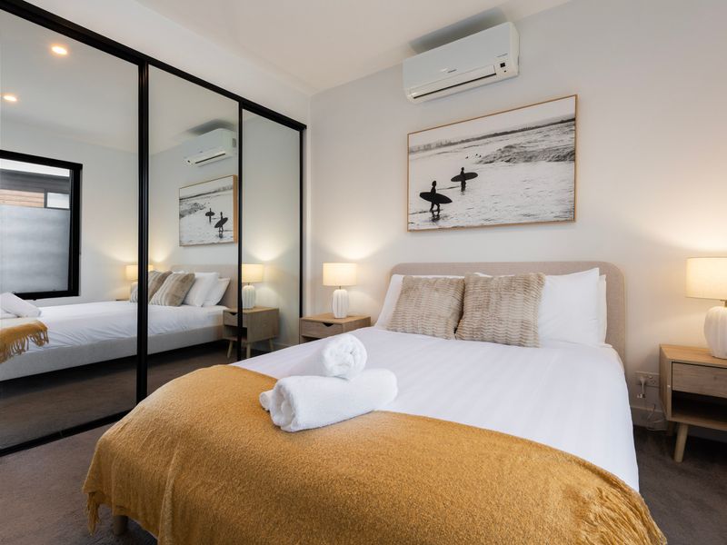 Guest bedroom with a bed and mirrored closet doors along the wall.