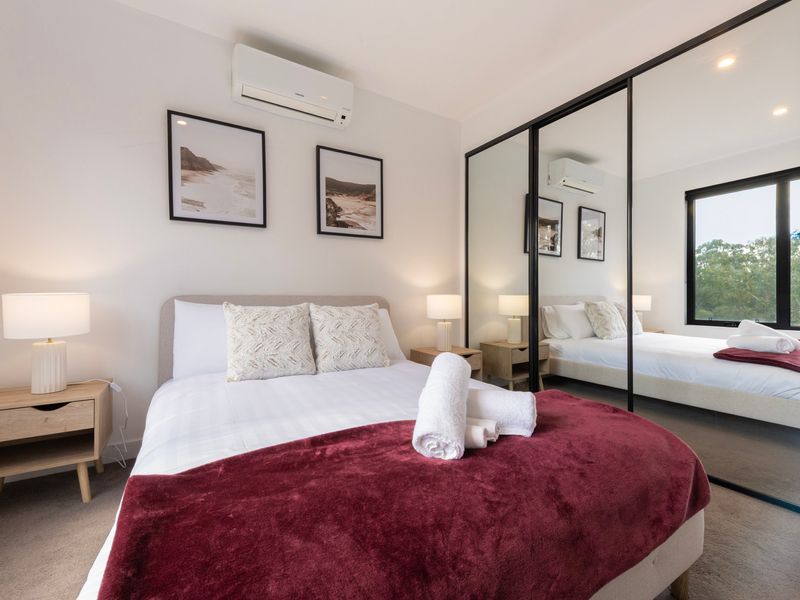 Wide view of the bedroom with mirrored wardrobes reflecting the room.