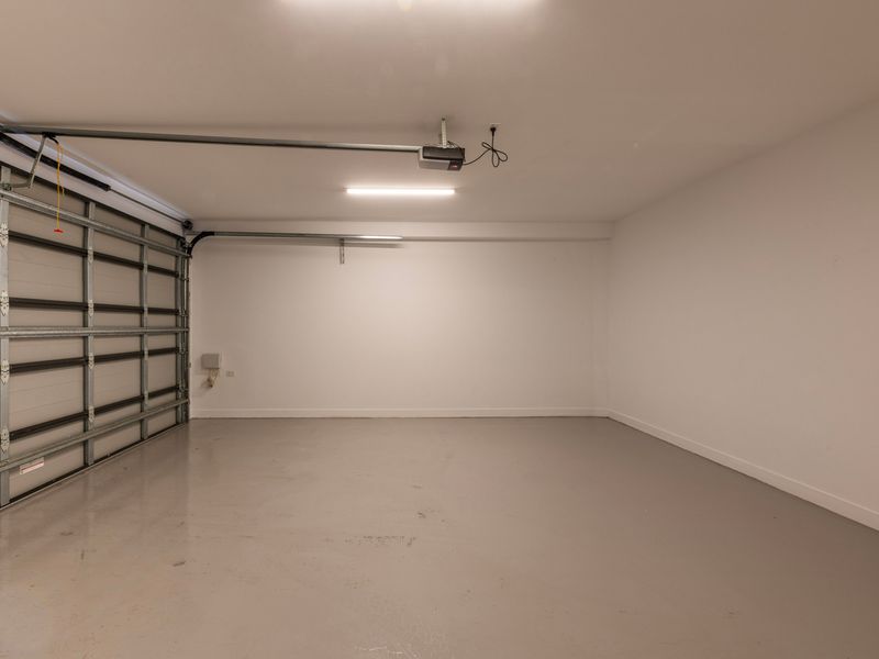 Clean and spacious empty indoor garage area with a sectional door.