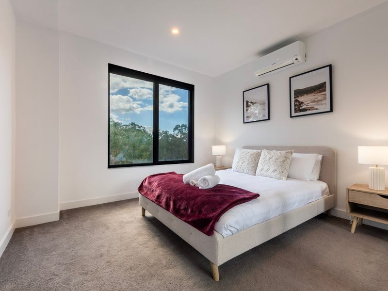 Bright bedroom with a bed featuring a burgundy throw blanket and side lamps.