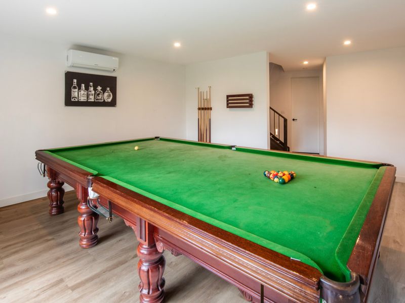 Spacious game room featuring a green felt pool table and hardwood floors.
