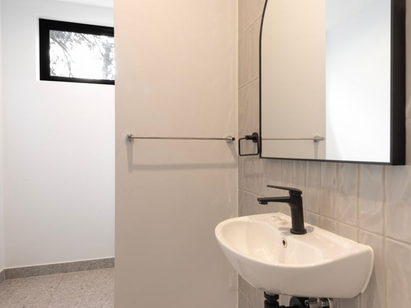Close-up of a modern sink faucet mounted over a white wall-mounted basin.