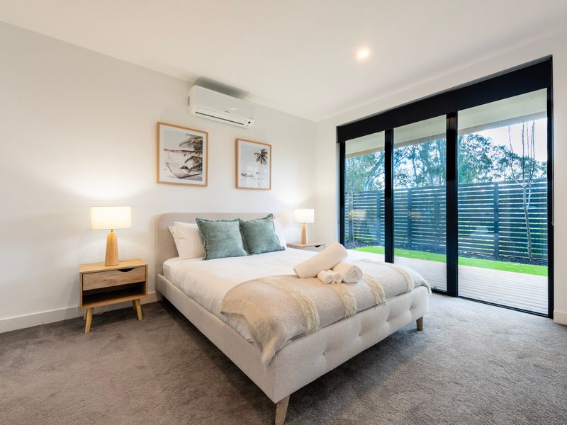 Light-filled bedroom with a bed positioned near sliding glass doors leading outside.