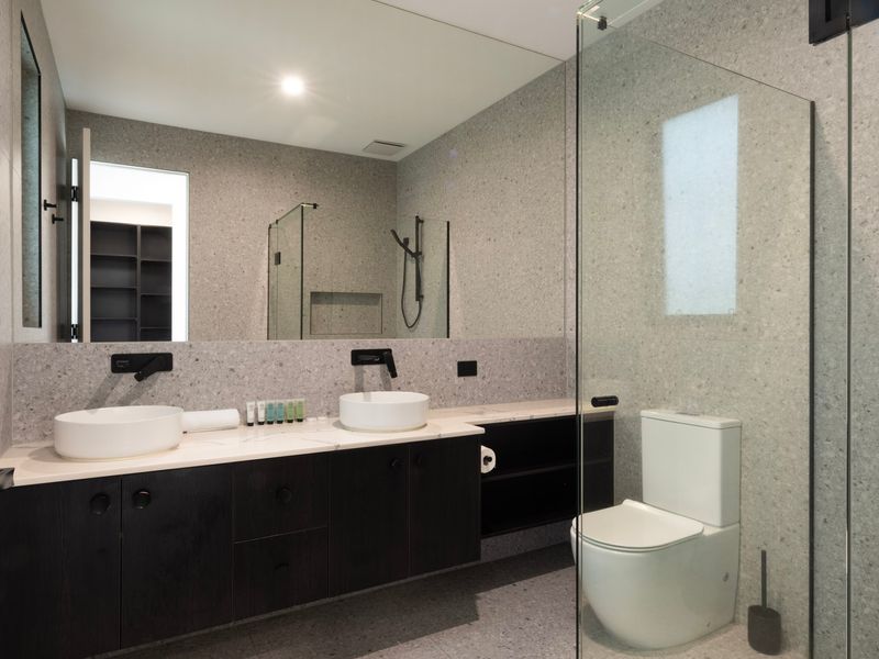 Sleek modern bathroom featuring a double-sink vanity and a separate toilet area.