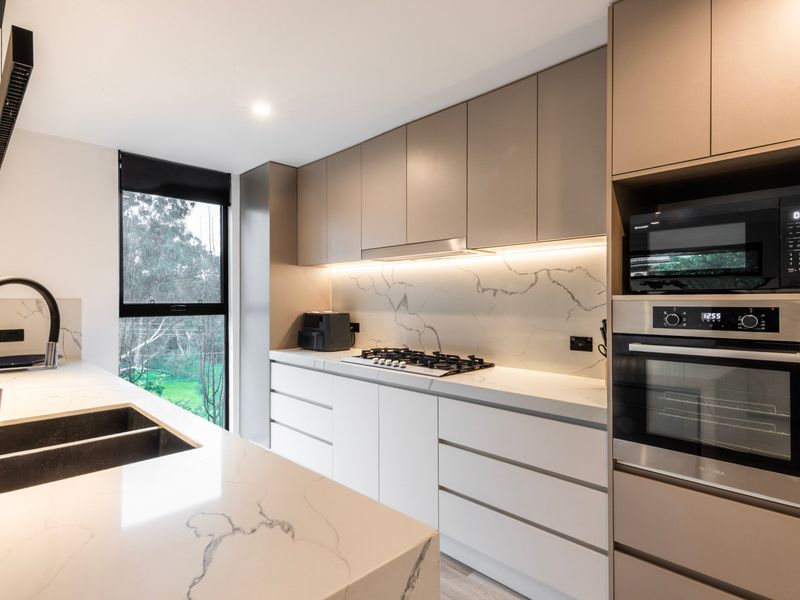Modern kitchen area featuring light countertops and built-in wall ovens.