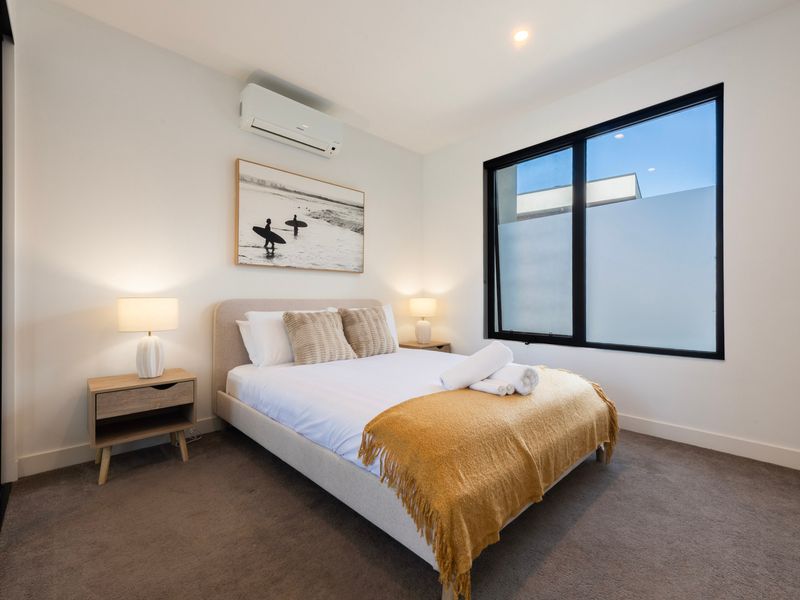 Bedroom featuring a yellow accent throw and a window overlooking exterior greenery.