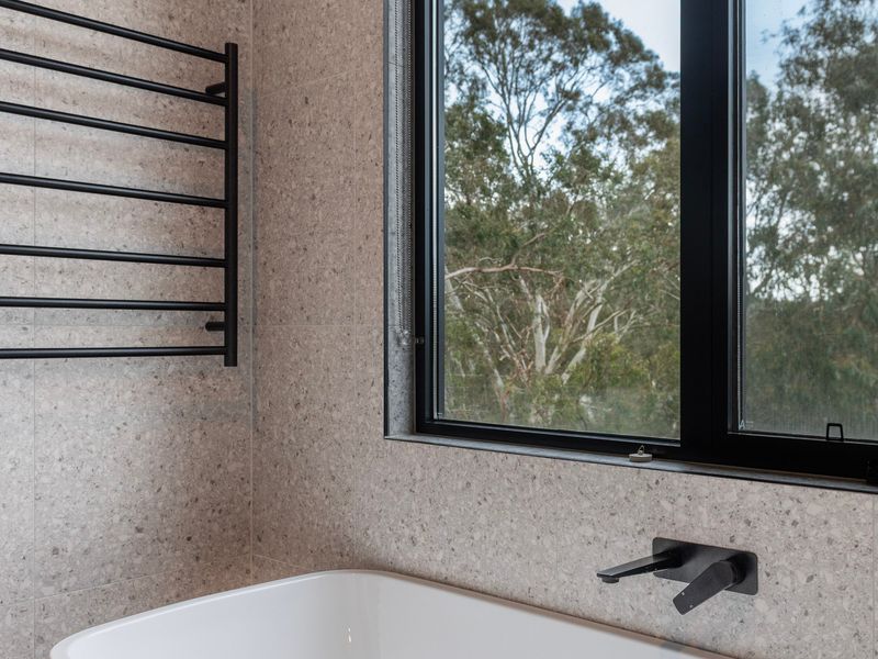 Bathroom interior showing a modern towel warmer rail mounted on a textured wall.