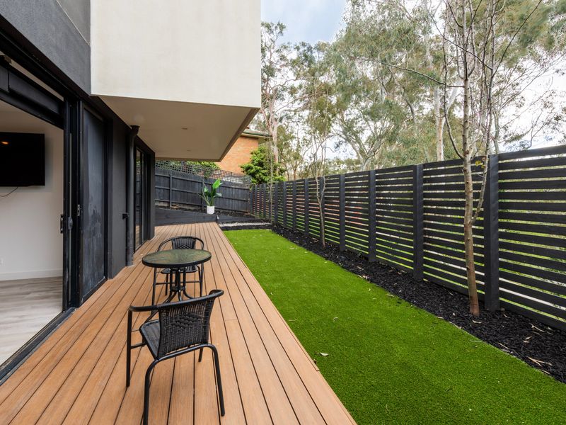 Covered outdoor wooden deck area looking out toward a small green lawn.