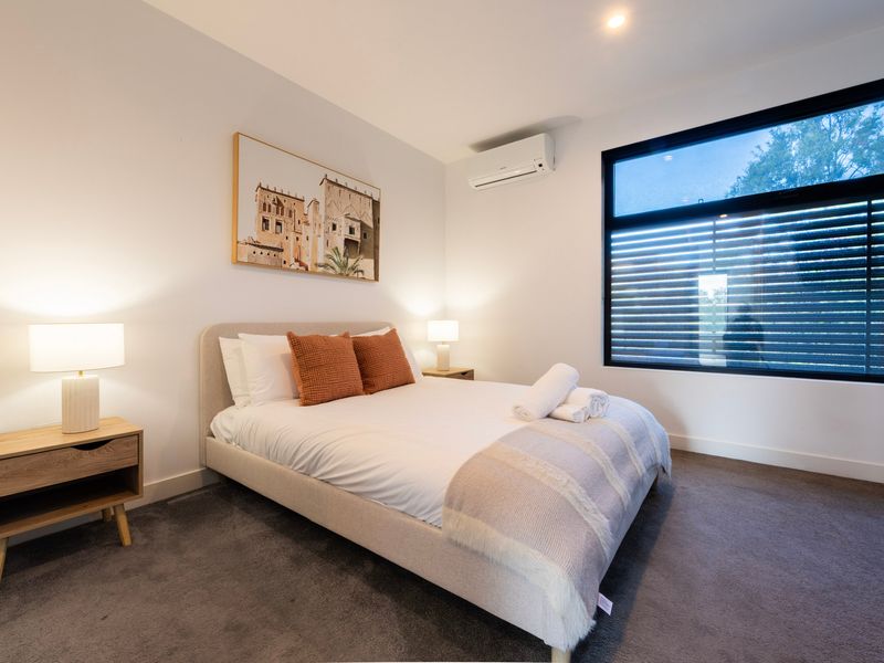 Bedroom setup showing a bed with orange accent pillows and a horizontal window view.