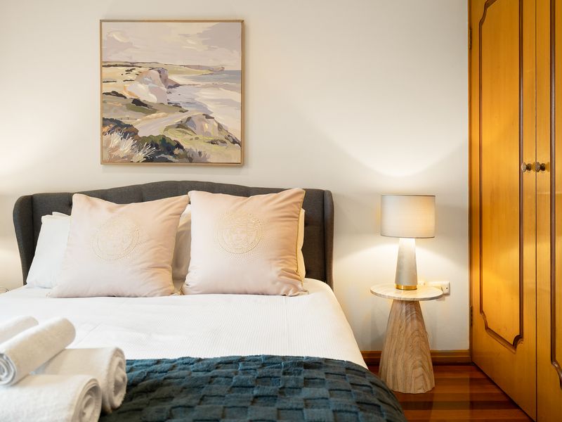 Bedroom showcasing neutral tones, a headboard, and decorative artwork.