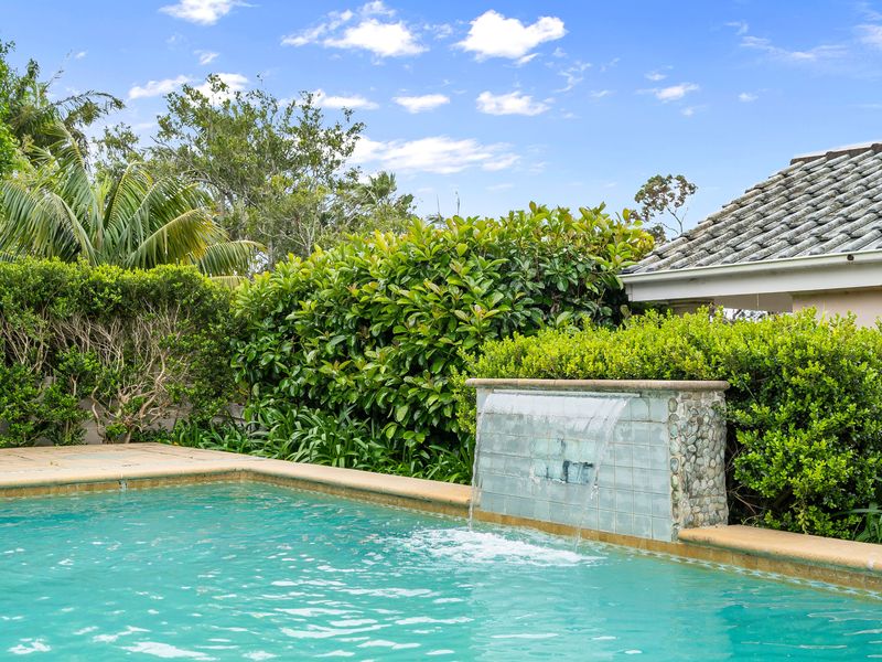 Sparkling swimming pool and patio area nestled against natural shrubbery.