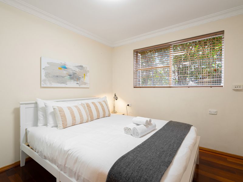 Bright and airy bedroom featuring crisp white linens and a large window.