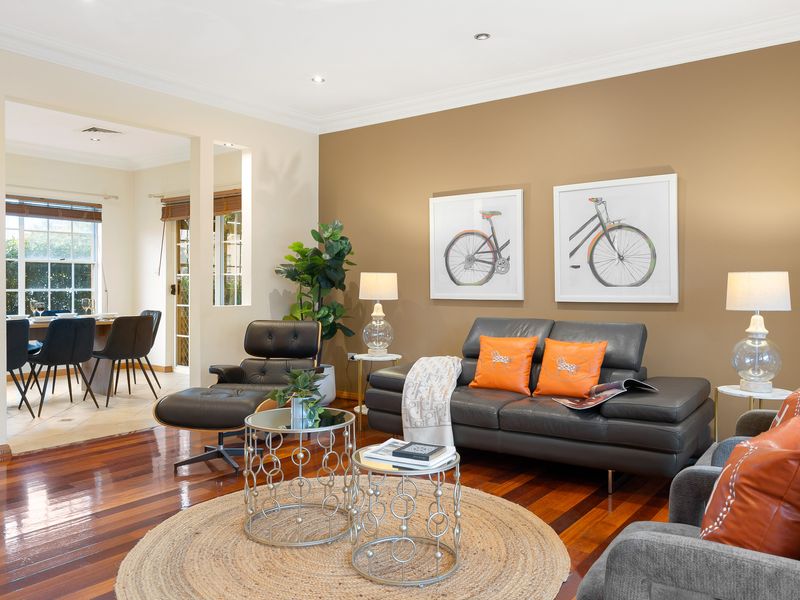 Living room featuring a dark leather sofa, colorful accent pillows, and wall art.
