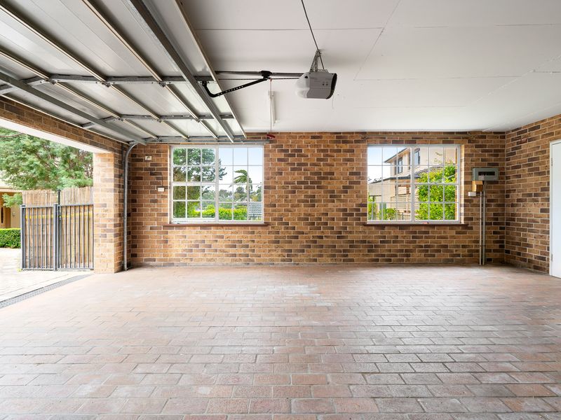 Spacious indoor double garage with brick walls and multi-pane windows.