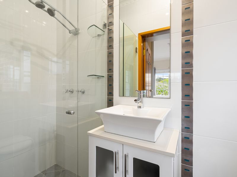 Modern glass-walled shower enclosure with white tiled walls.