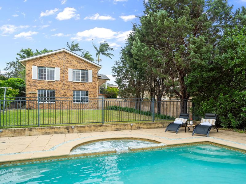 Rear view of the property showcasing the backyard pool and surrounding greenery.