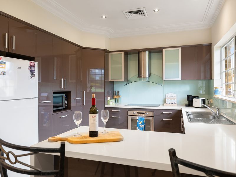 Modern kitchen featuring white countertops, wooden cabinetry, and stainless steel appliances.