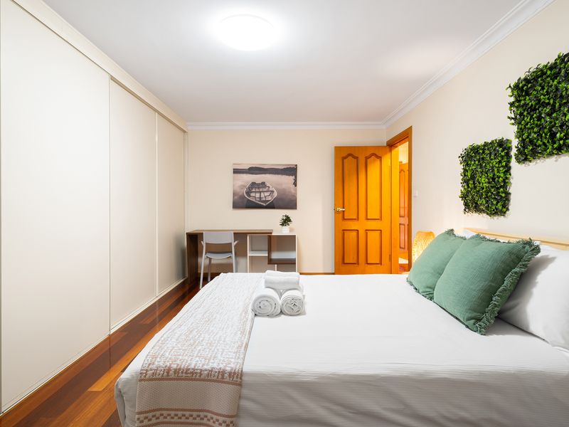 Bedroom view highlighting neat bedding and minimalist wood paneling.