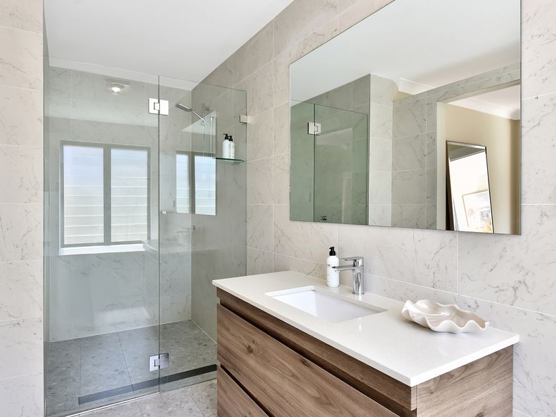 ChatGPT said:  Modern bathroom featuring a sleek glass shower, large mirror, and elegant vanity with wood finish.