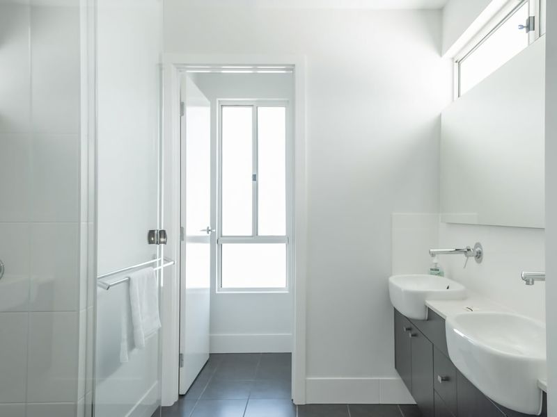 Modern, bright bathroom with dual sinks and ample natural light.