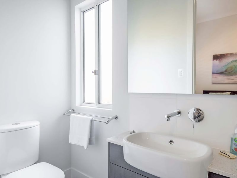 Refresh and recharge in this light-filled, minimalist bathroom featuring sleek modern fixtures and a clean, serene aesthetic.