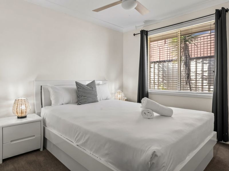 Second queen bedroom with soft linens and ceiling fan.