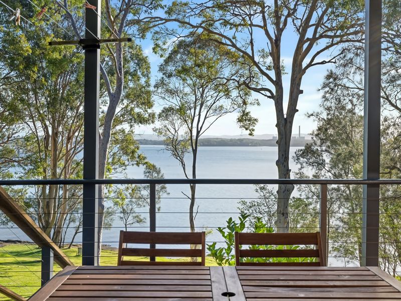 Peaceful deck setting overlooking the water and trees.