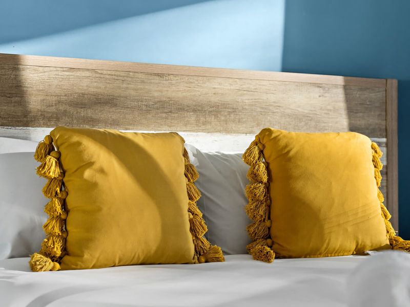Plush king bed with fresh linens and sunny yellow accents.