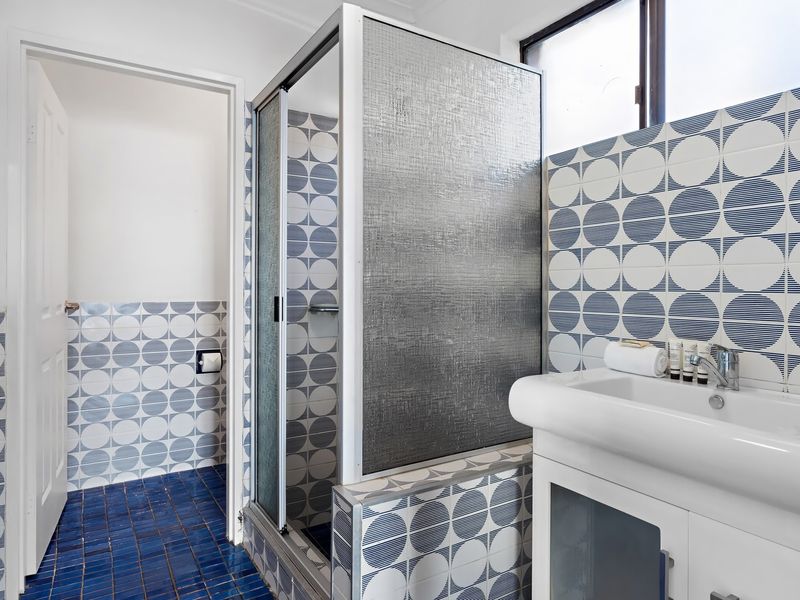 Bathroom with walk-in shower and patterned feature tiles.