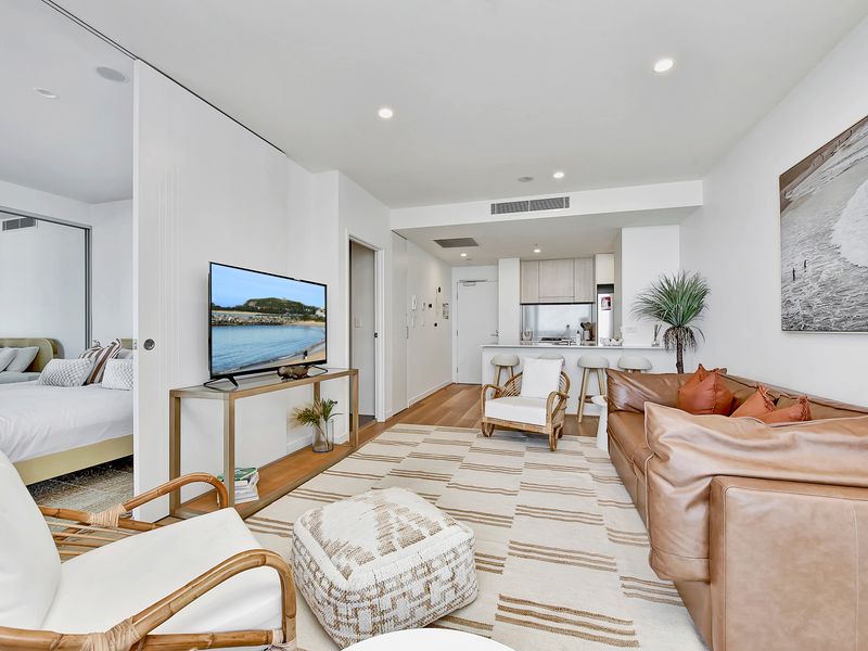 Open-plan living area with modern coastal decor, full kitchen and comfortable lounge seating.