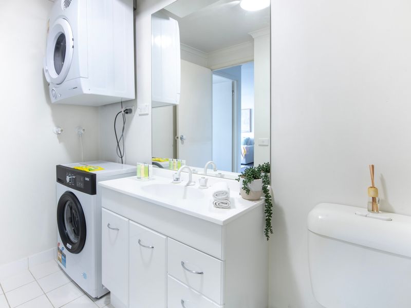 Full bathroom/laundry featuring ample bench space and storage